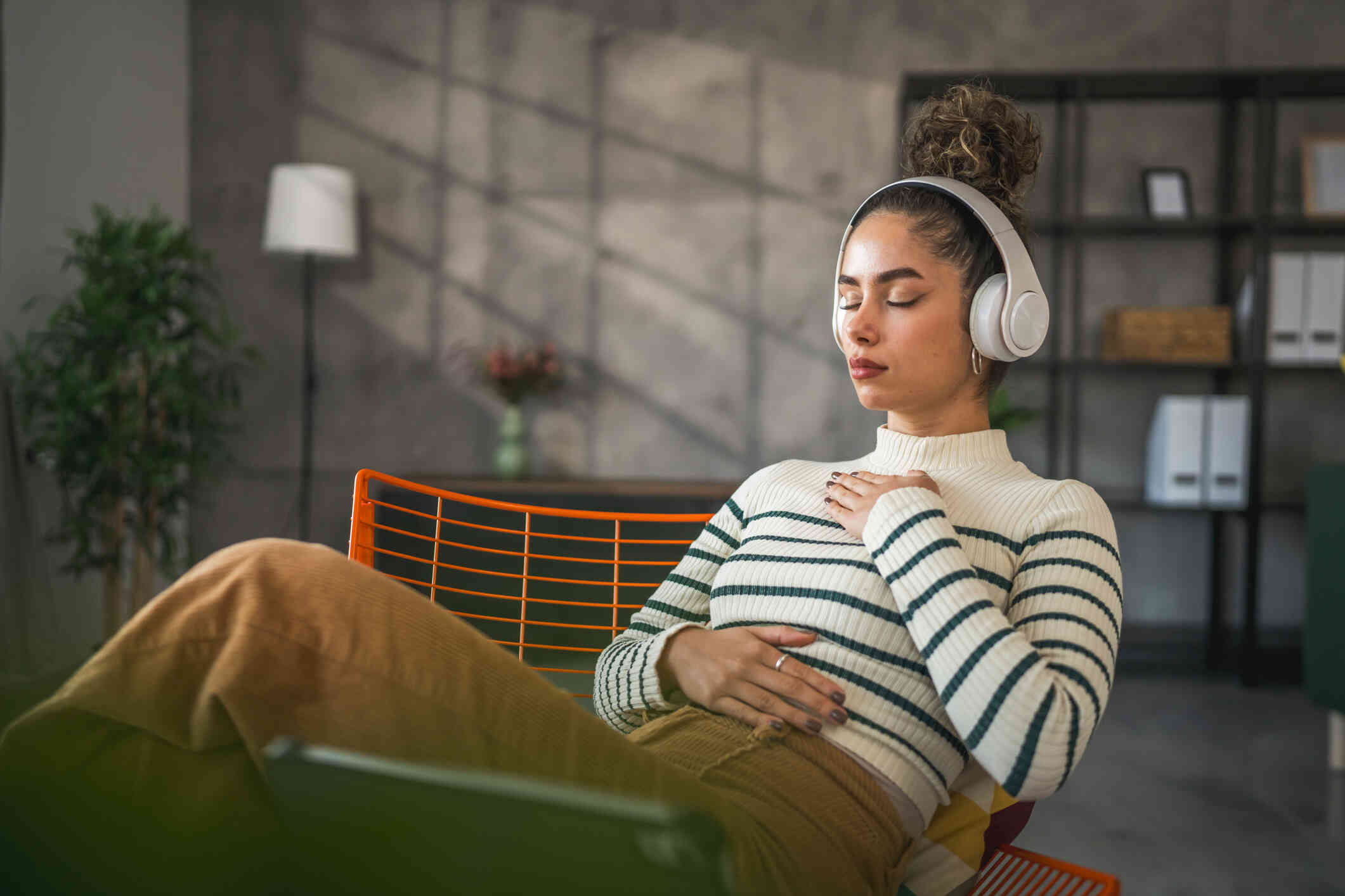 A woman in black and white stripe shirt wears an headphone. She appears to be deep in thought.